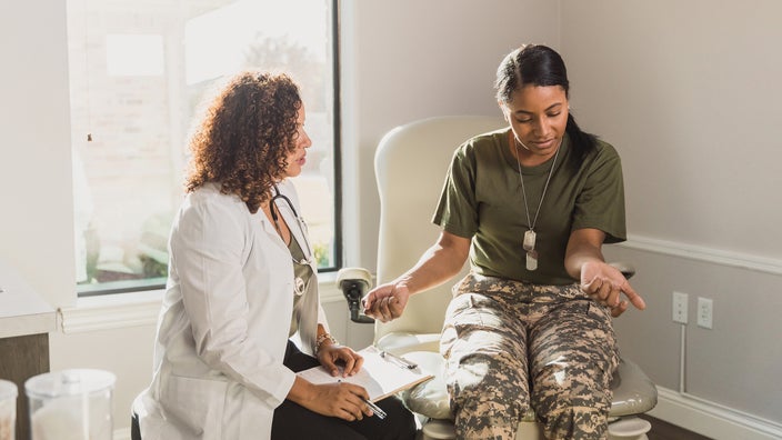 An army vet is having a consultation with their doctor. They’re showing their forearms.