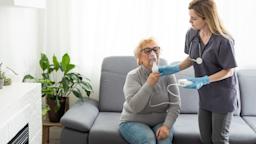 A nurse helps a woman with an at-home nebulizer treatment.
Sinenkiy/iStock via Getty Images
