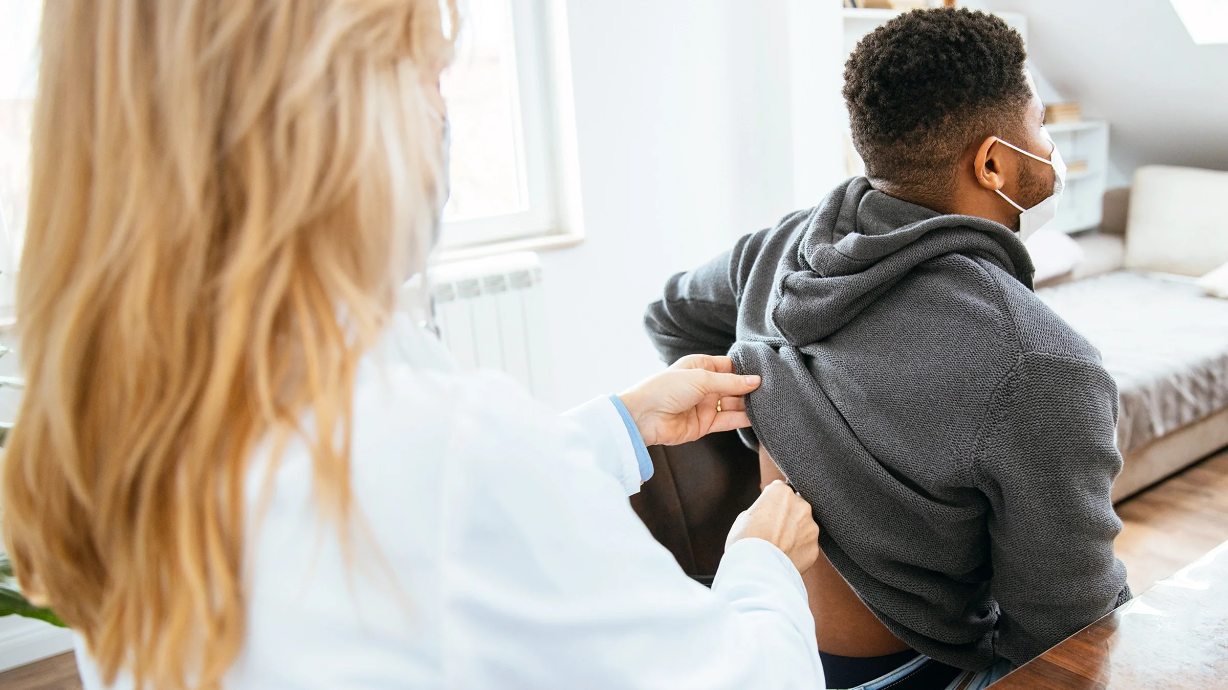 A healthcare provider examines a patient’s back.