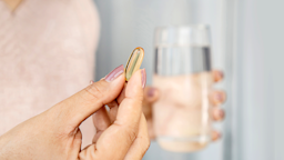 Close-up hand holding capsule pill with a glass of water.
Doucefleur/iStock via Getty Images Plus
