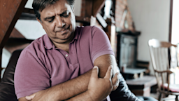 Man grabbing elbow in pain. He is wearing a light red polo shirt.
RealPeopleGroup/E+ via Getty Images

