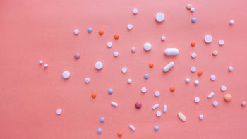 Drug costs and savings: Expensive generics: scattered pills pink background 1421653280