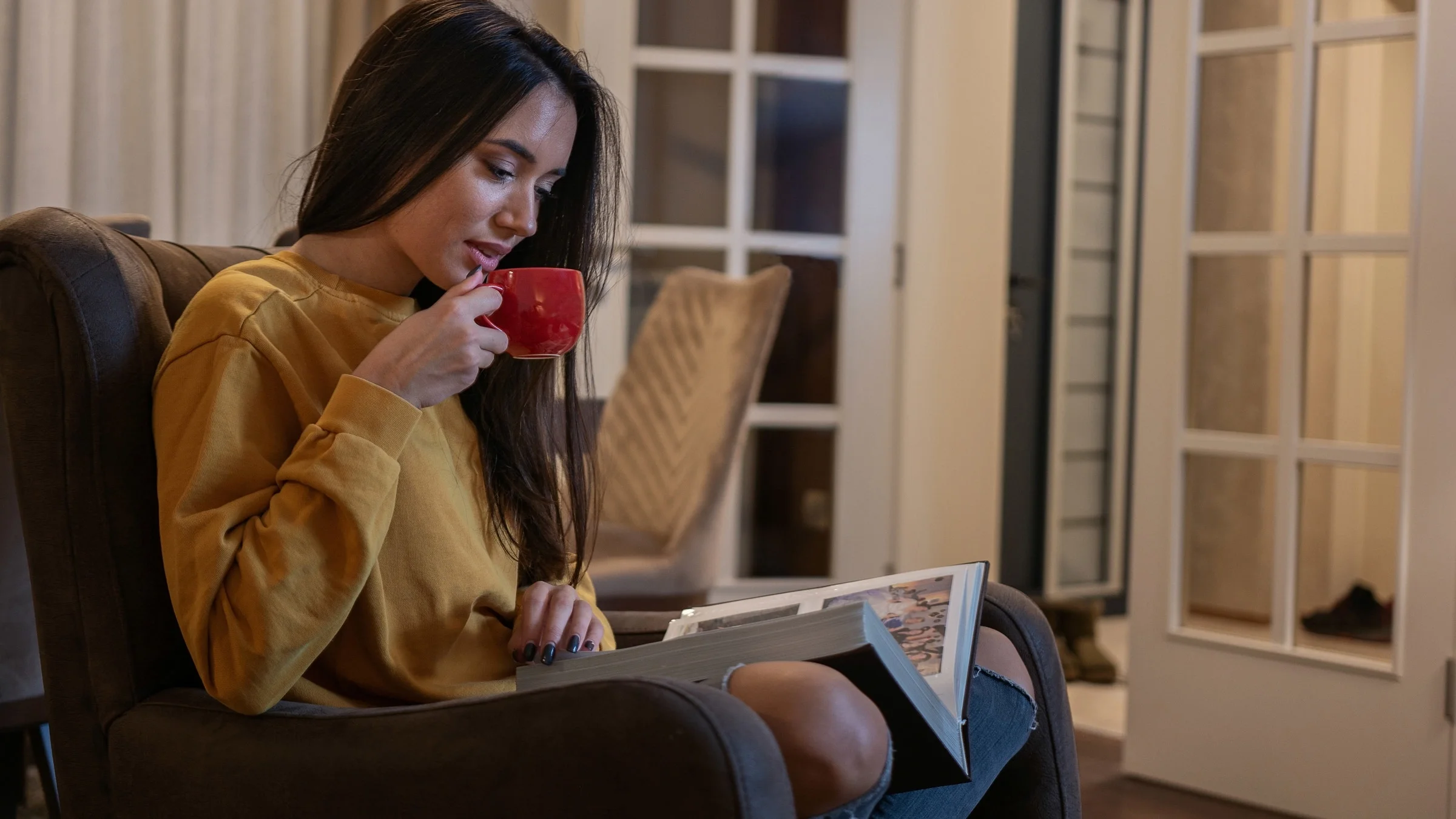 A person drinking tea and looking at a photo album.