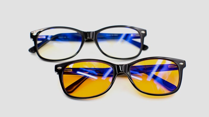 Two pairs of blue-light glasses on a plain, light-gray background.