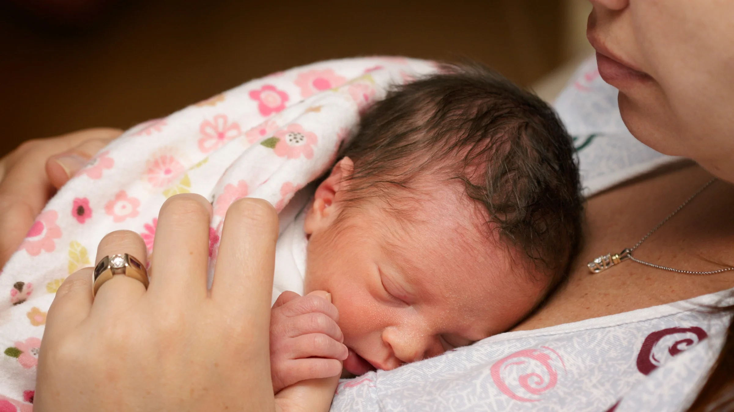 Close-up of a mother holding their premature baby to their chest.
