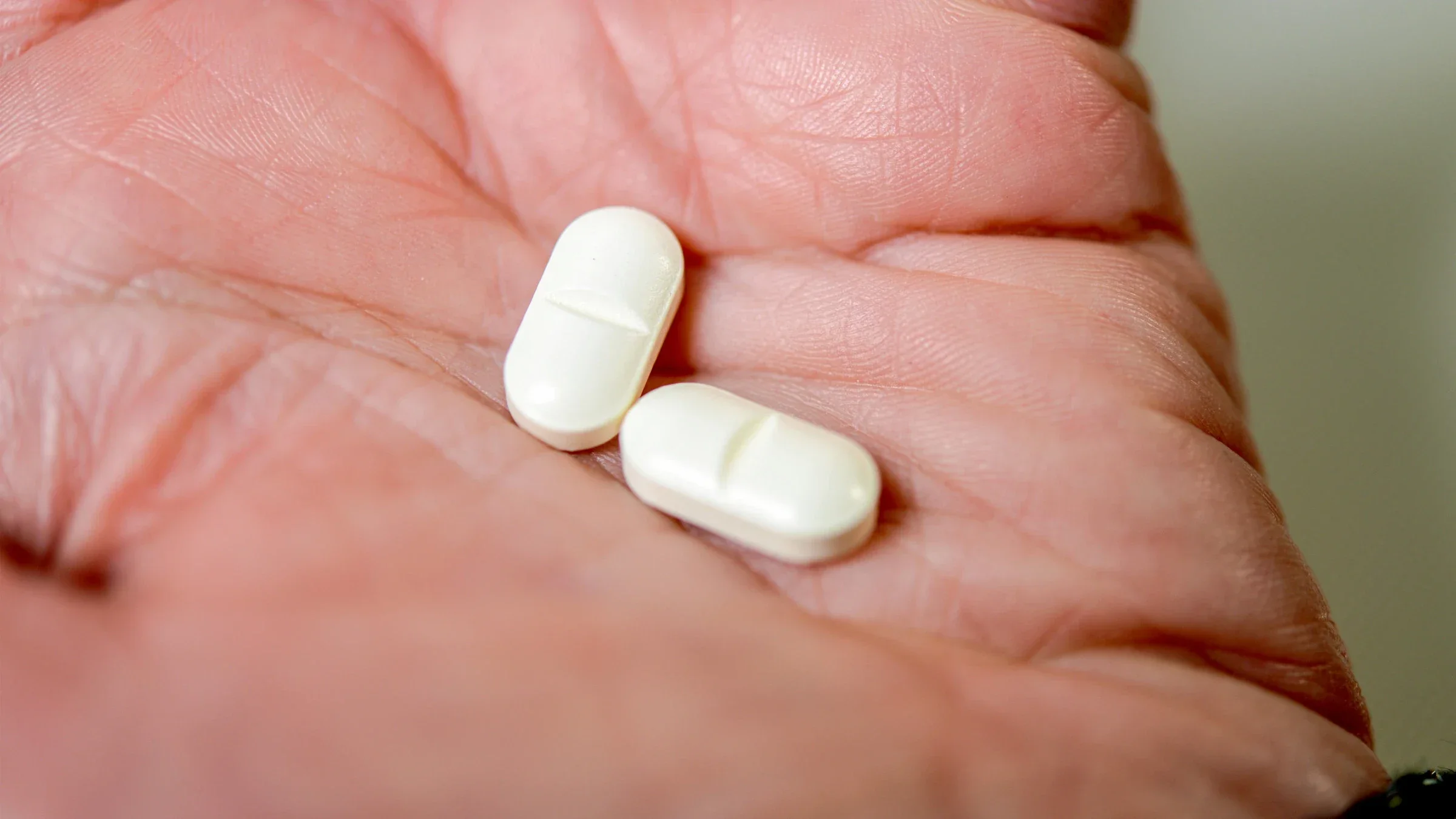 Two white oblong pills sit in the palm of a hand. 
Karl-Hendrik Tittel/iStock via Getty Images
