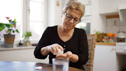 Senior woman in her kitchen taking her medication.
luza studios/E+ via Getty Images