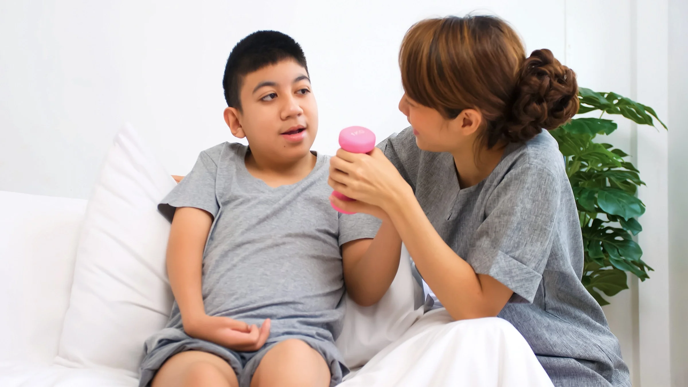 Mother helping son do physical therapy exercises at home.