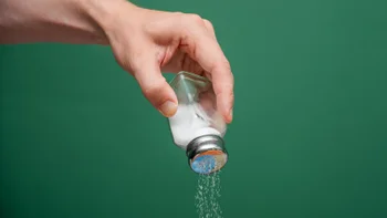 diet-nutrition: hand holding salt shaker 2248550202