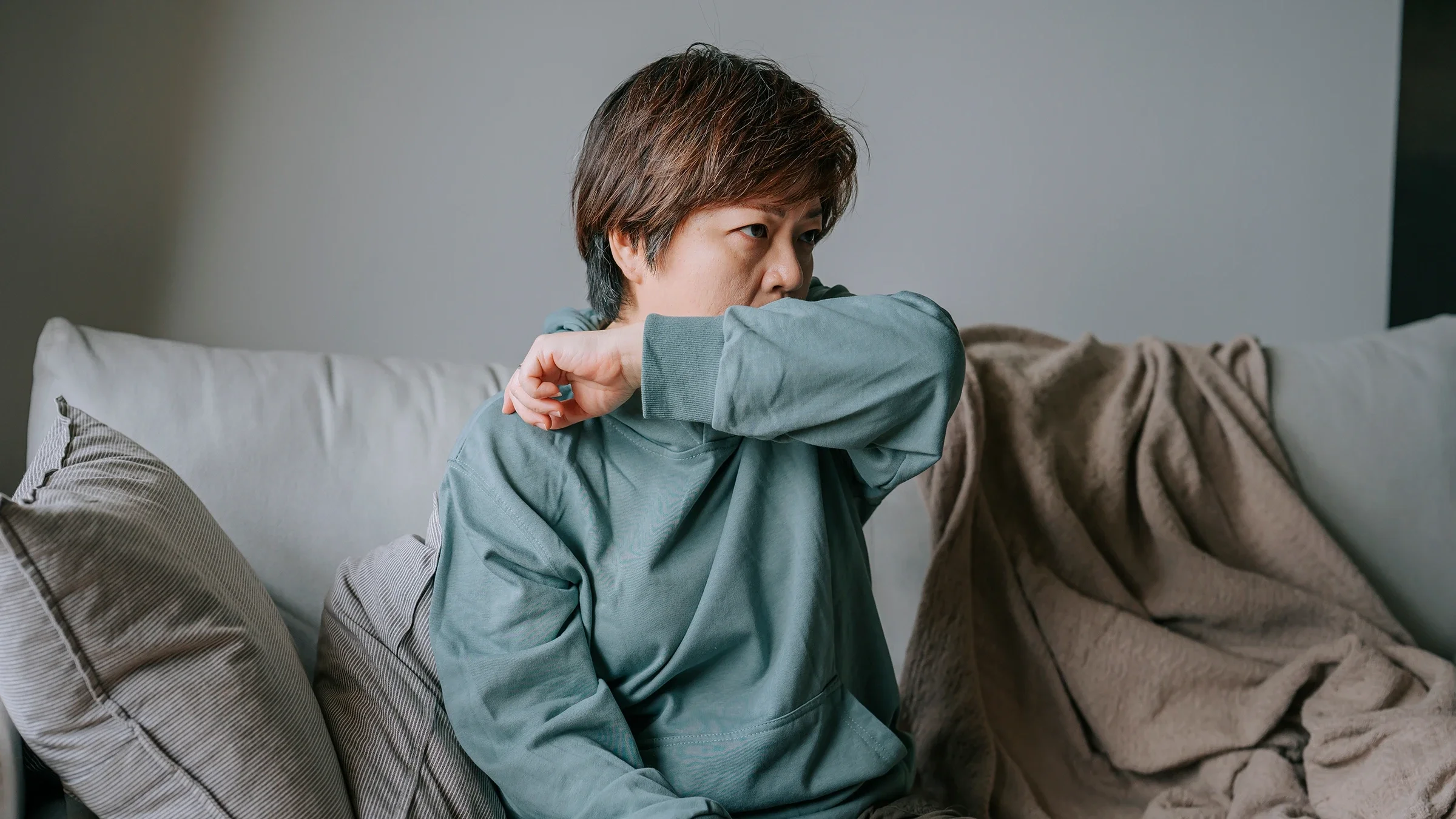 Woman coughing into elbow.