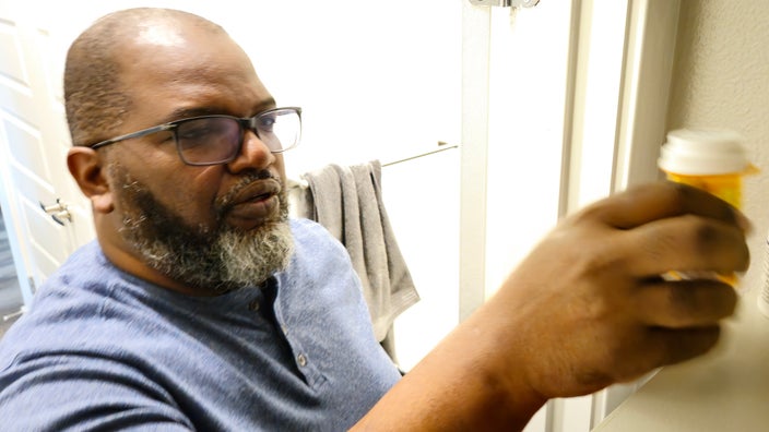 A man reaching for a pill bottle from his medicine cabinet.