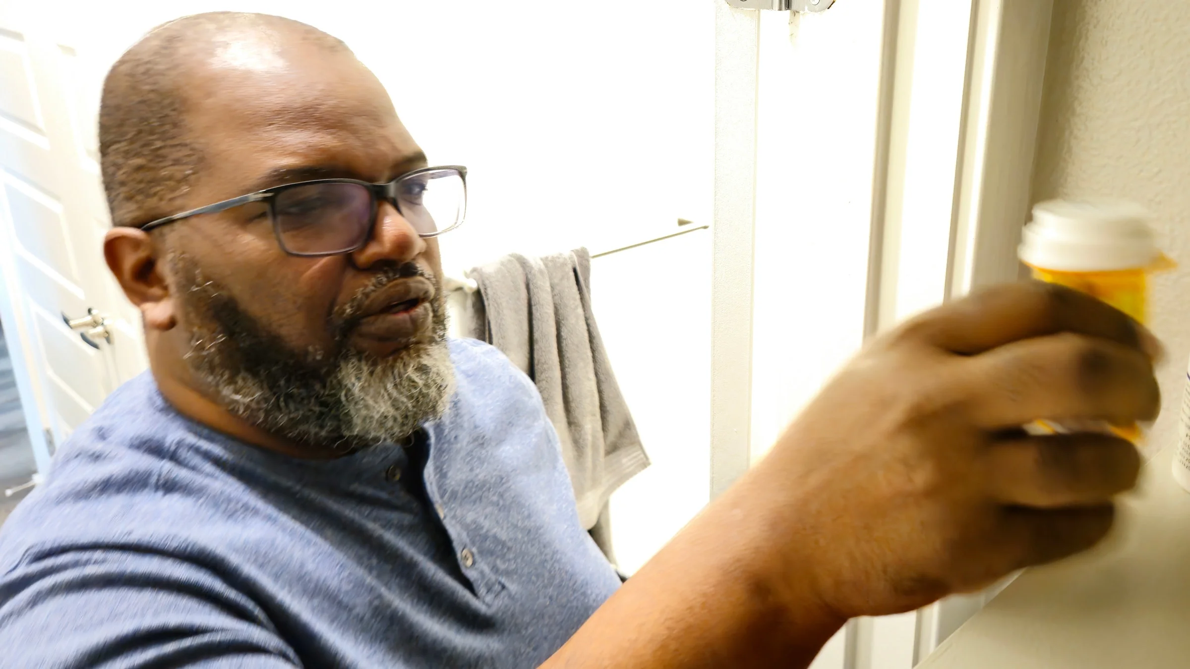 A man reaching for a pill bottle from his medicine cabinet.