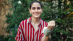 Portrait of a young woman cancer survivor. She is using a wrist blood pressure cuff device.
Fatma Secil Karademir/E+ via Getty Images

