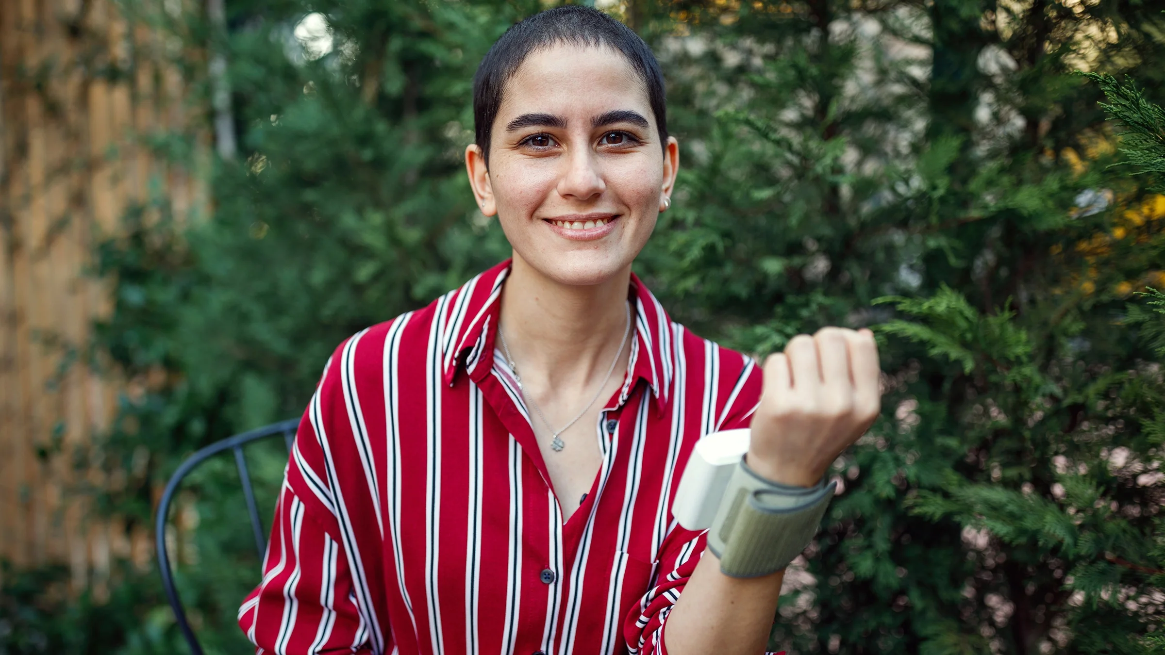 Portrait of a young woman cancer survivor. She is using a wrist blood pressure cuff device.