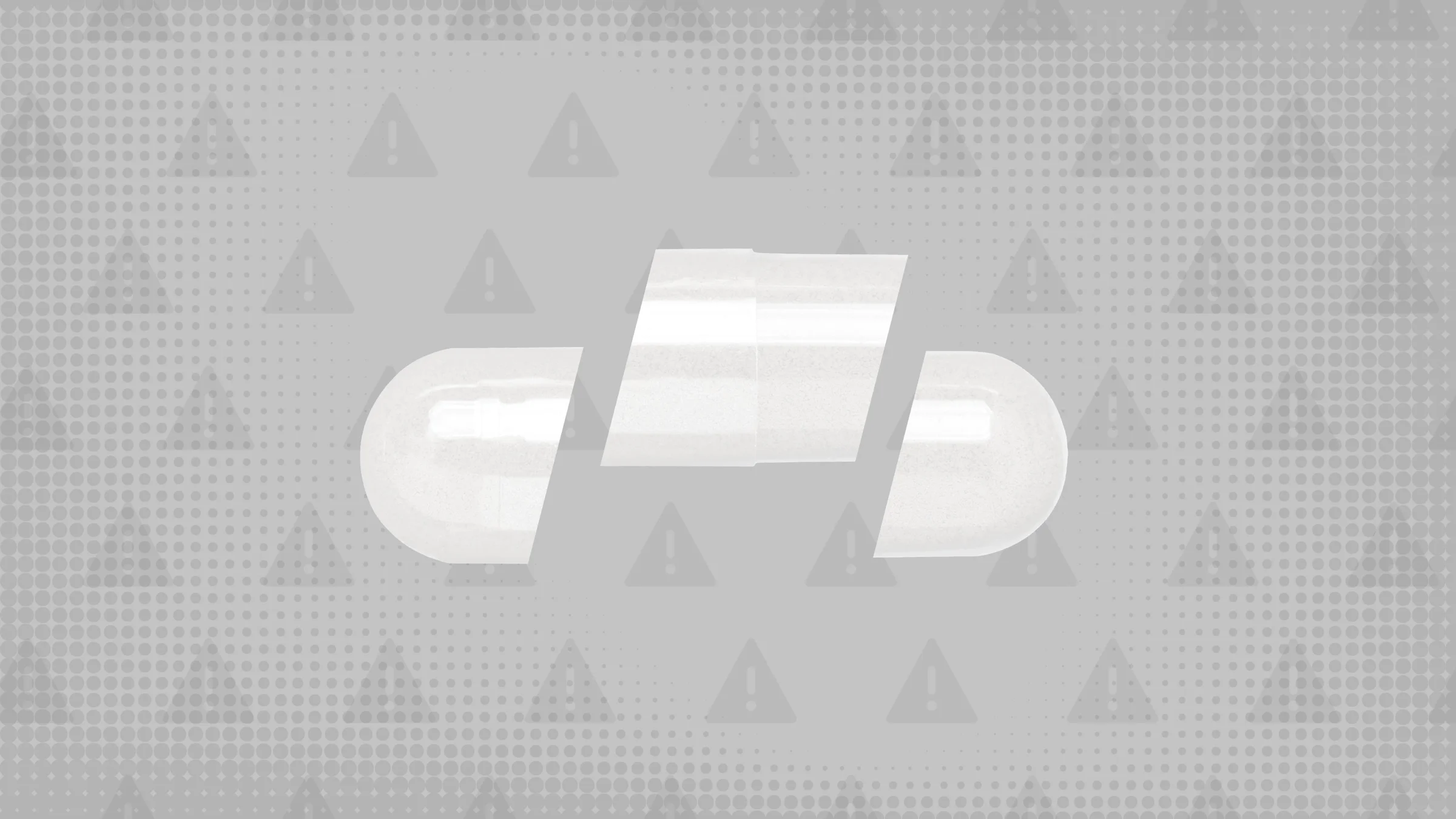 Medium-gray background with texture and warning sign pattern. In the center of the frame is a white capsule pill cut into thirds. 