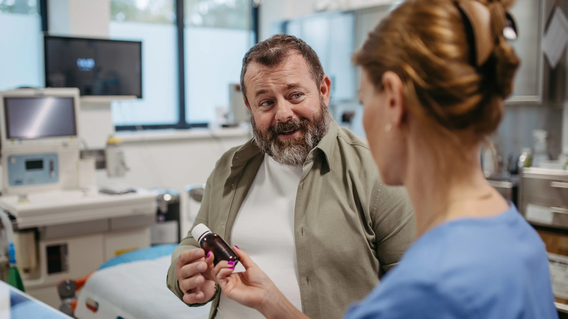 A doctor explaining a pill bottle to a plus-size patient.