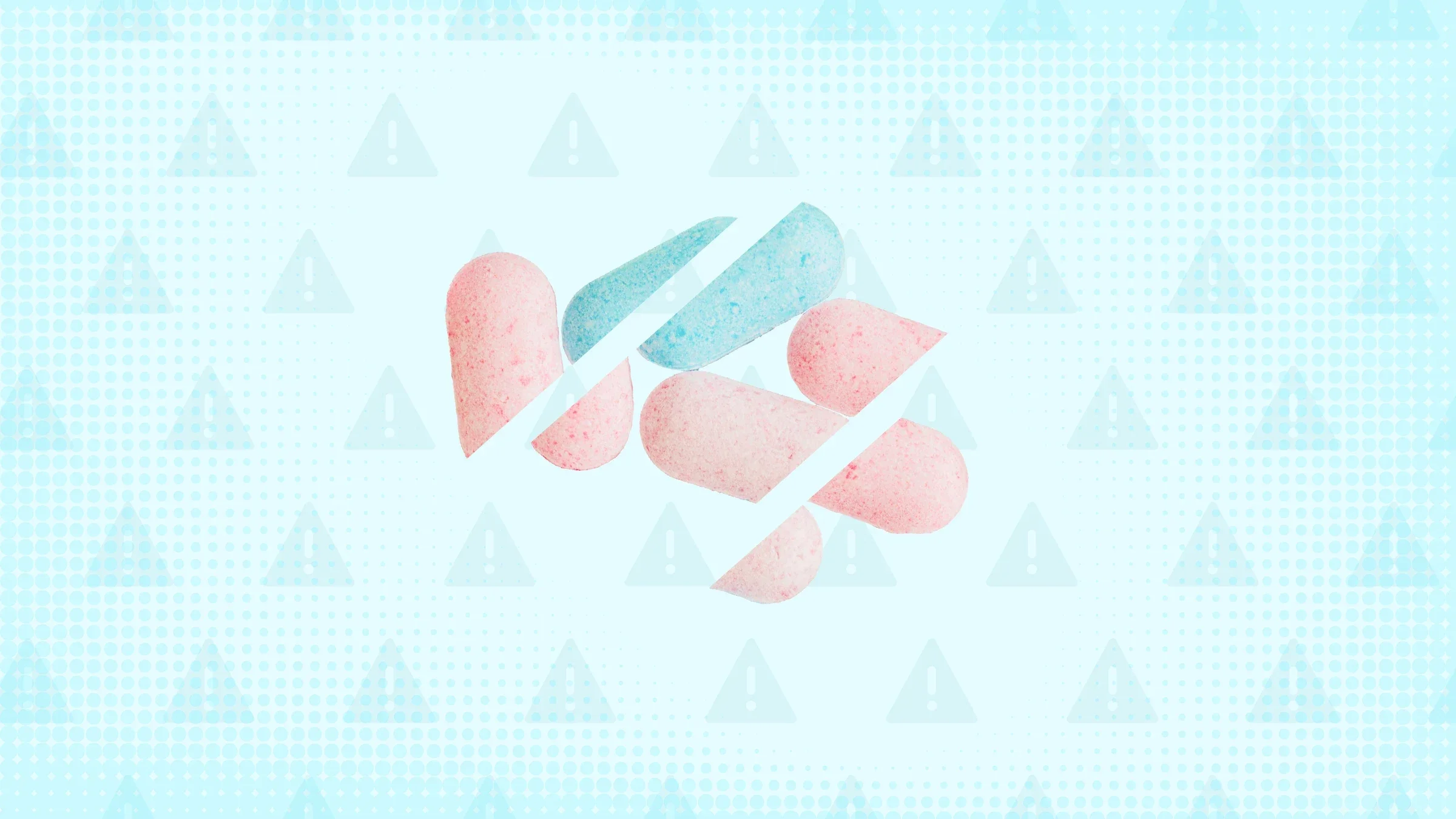 Light blue background with texture and warning sign pattern. In the center are pastel colored pills cut into thirds. 
GoodRx Health