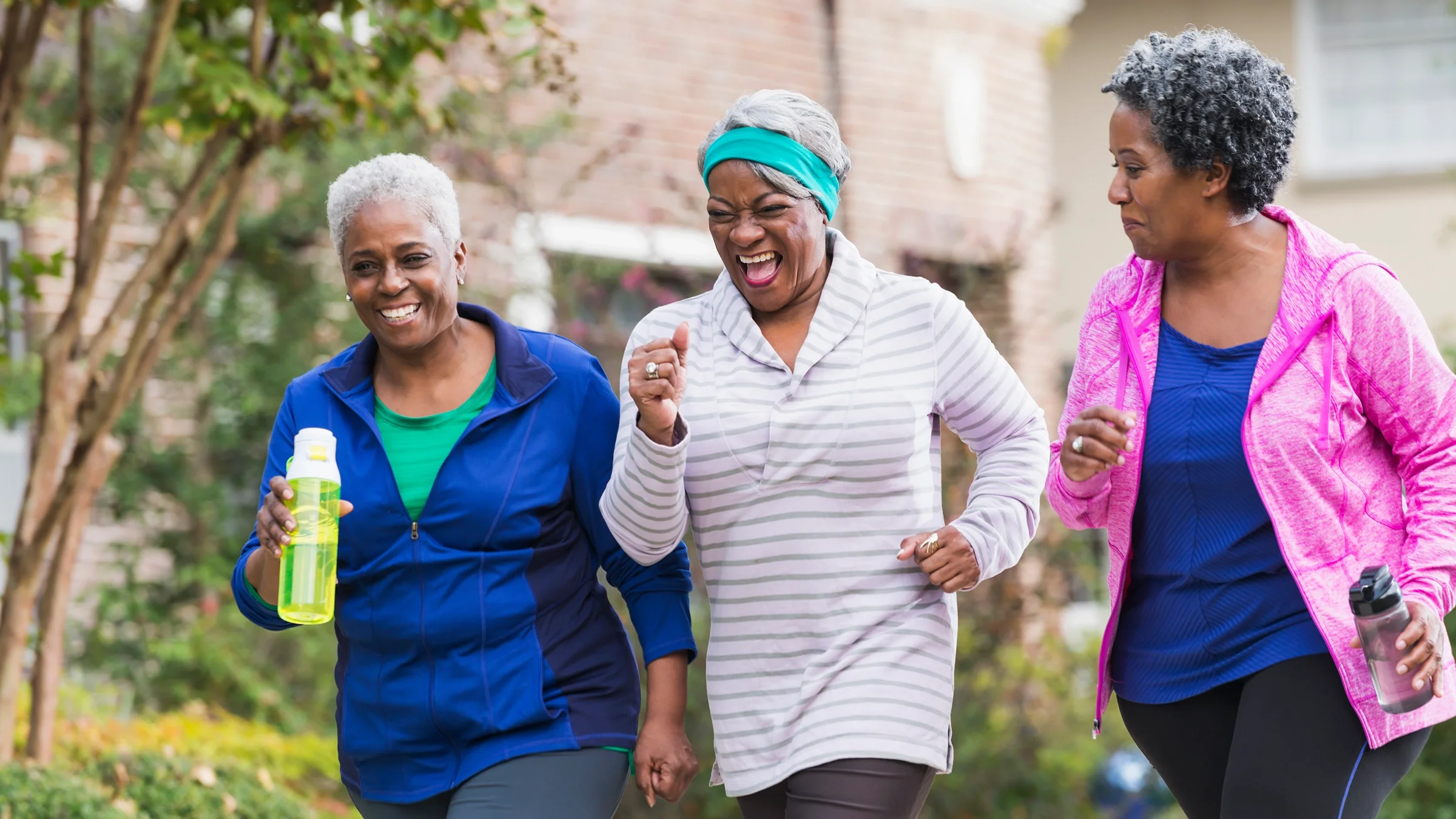 Three older women laughing and smiling as they are power walking.