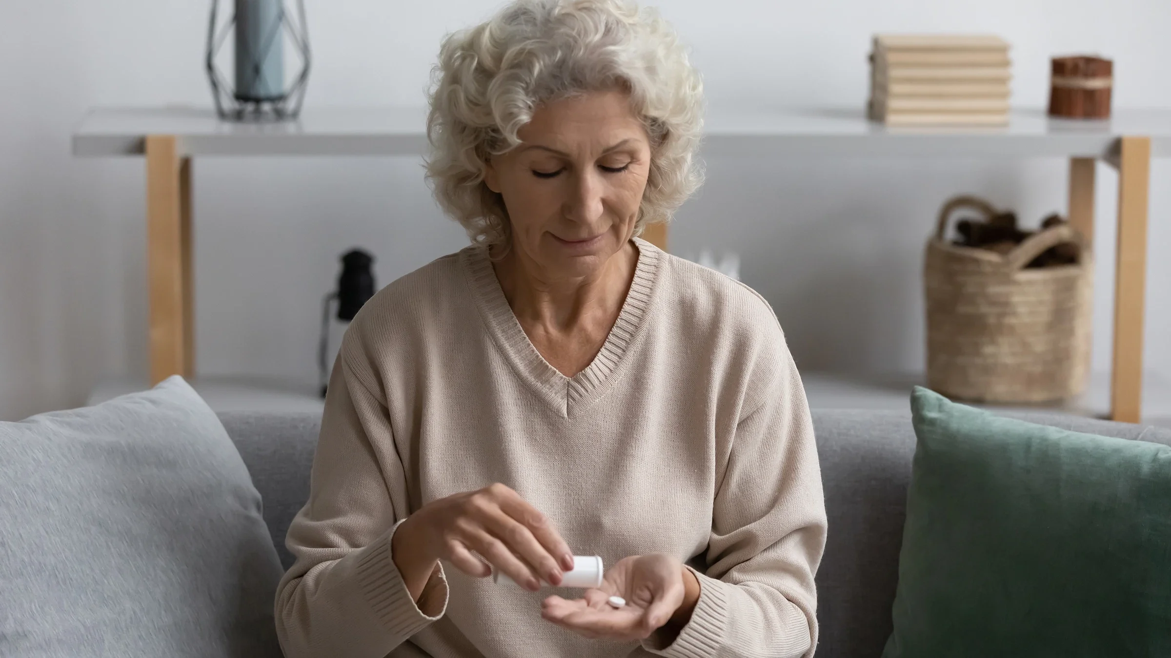 Older woman sitting on couch taking her medicine.