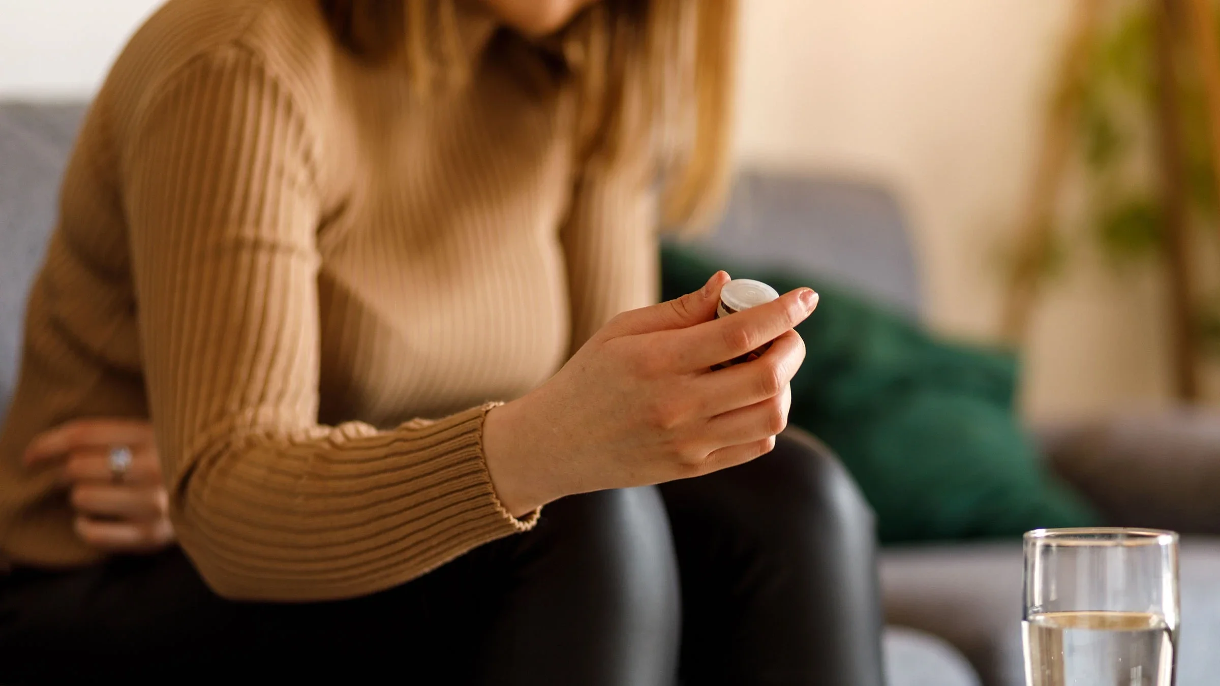 A woman sits on her sofa as she prepares to take her medication.