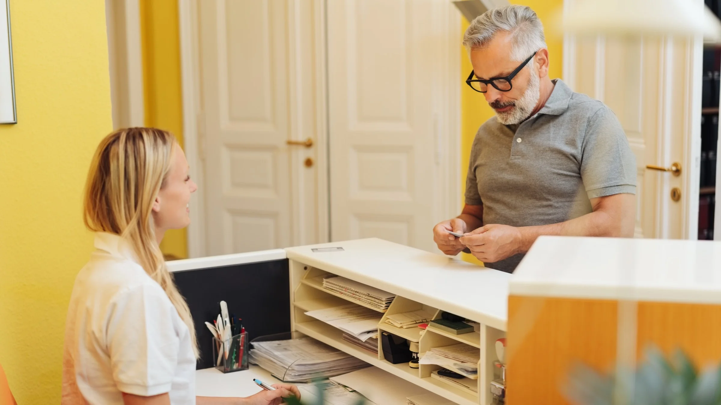 A patient handing a card to a receptionist. 