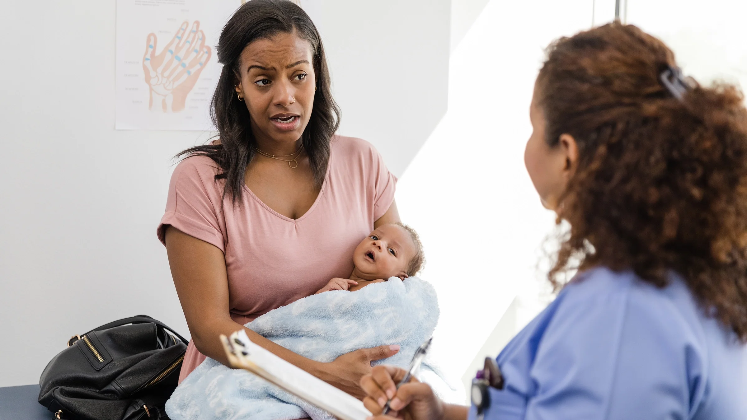A mother holds her newborn son at a medical appointment.