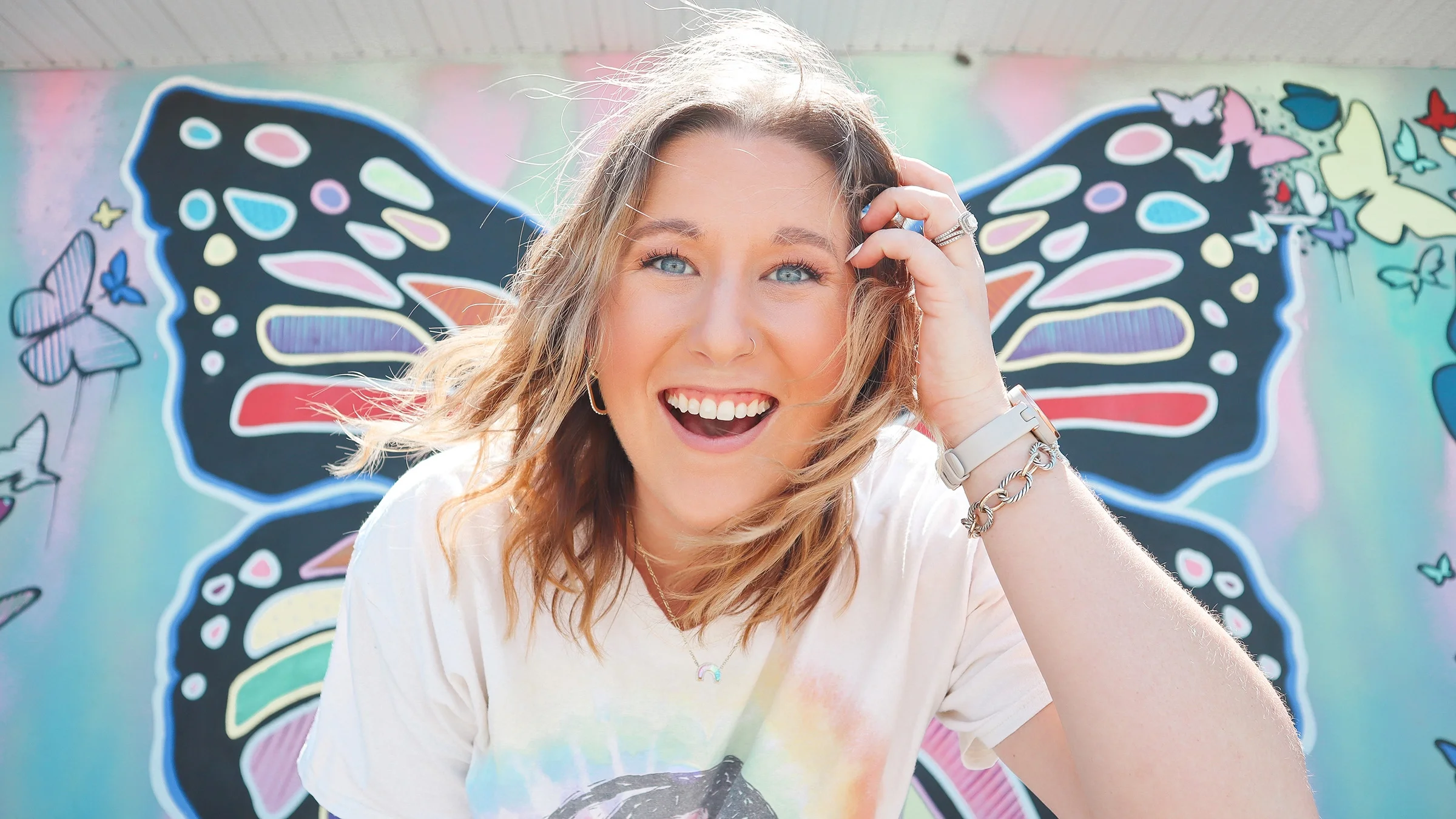 Portrait of Amanda Young, outdoors, with a butterfly mural behind her.
