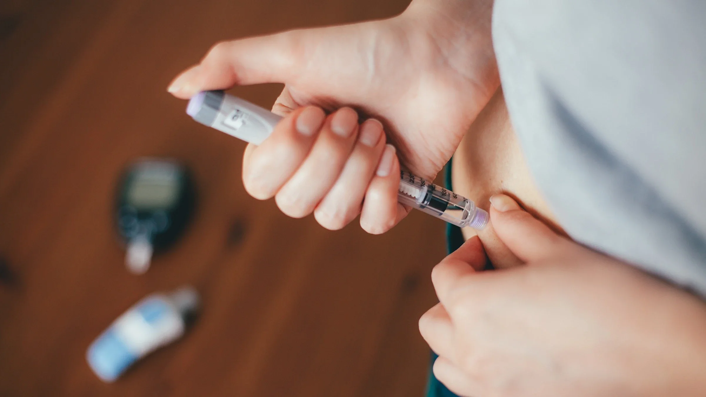Close-up of a person injecting their abdomen with insulin pen.