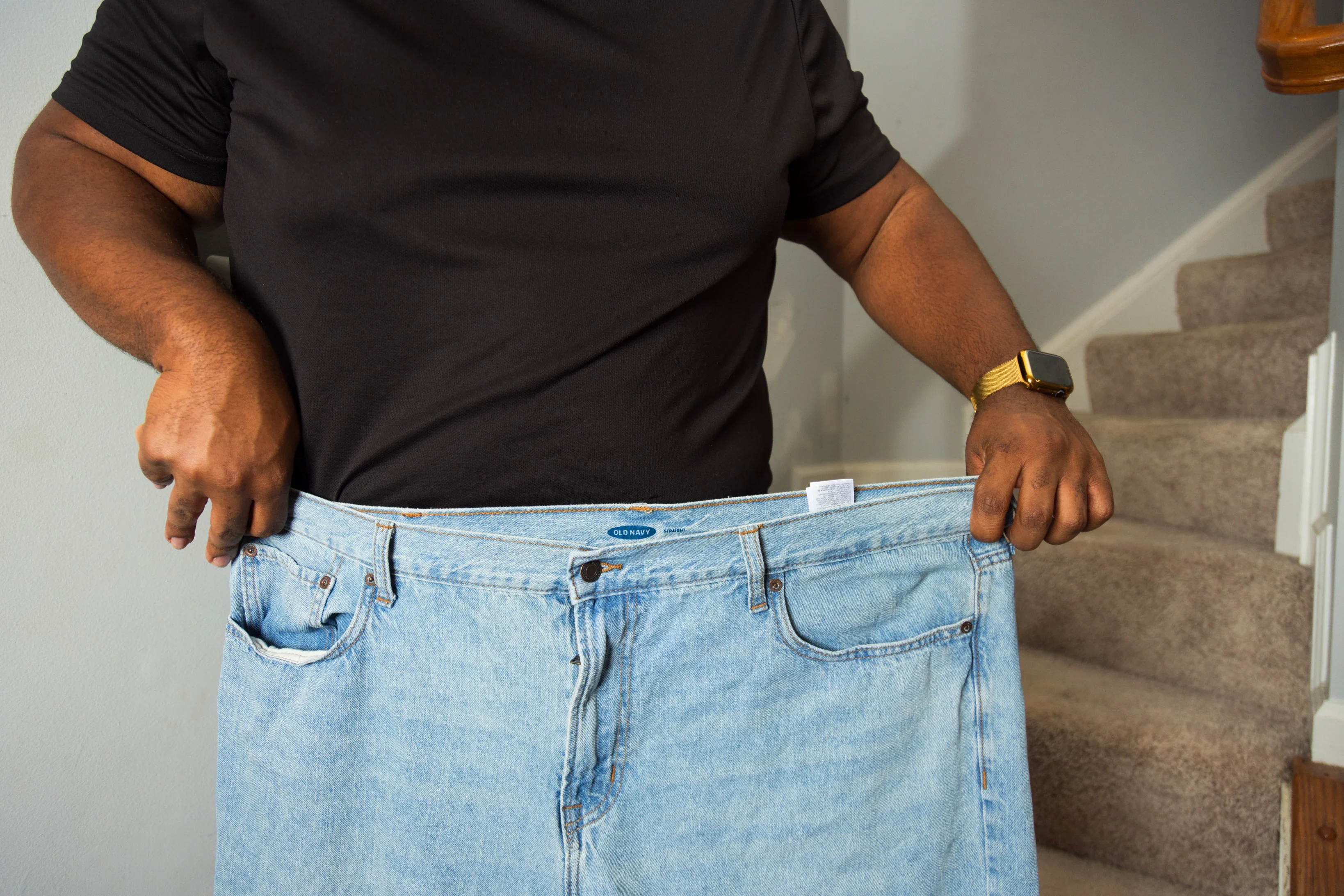 Shawn Pennix shows off his weight loss and compares his waistline — now size 42 — to an old pair of size 48 jeans. He has lost more than 70 lbs. 