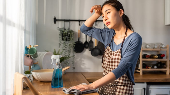 A person cleaning a kitchen and feeling stressed out.