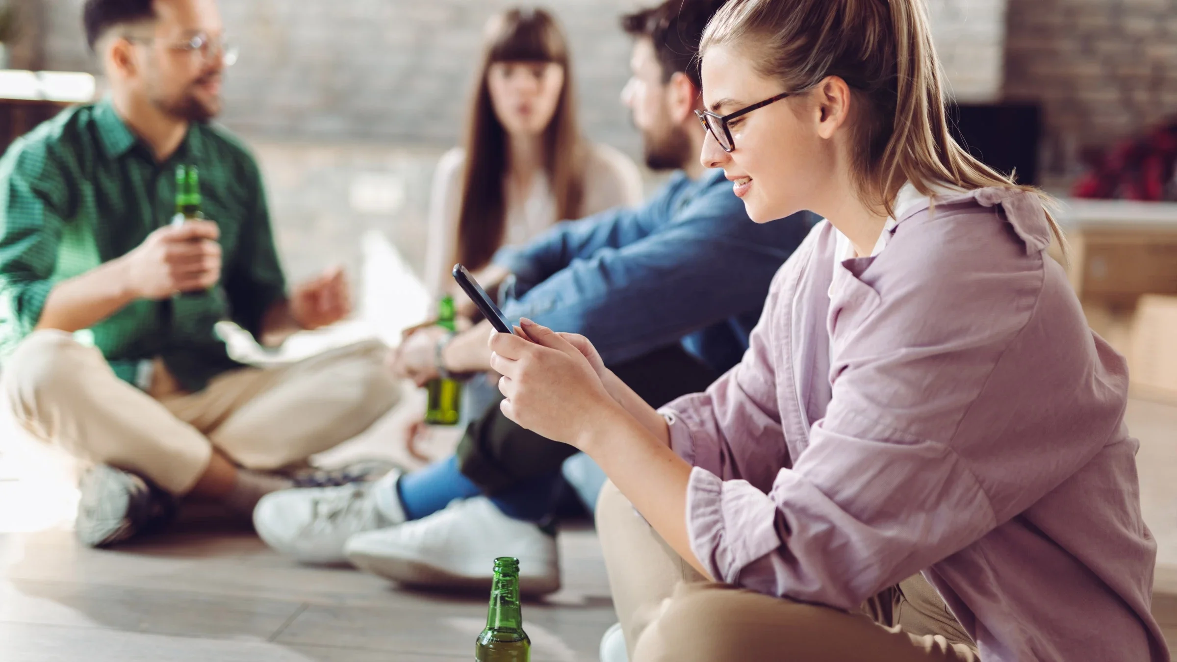 A person using their phone among friends drinking beer. 