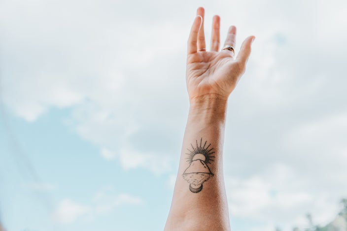Rachael Brooke Hoppock’s forearm tattoo, featuring a sunset and mountain, is pictured in a close-up.