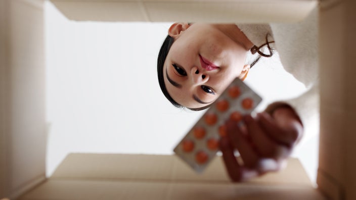 A person reaching into a box to get pills, shot below from inside the box.