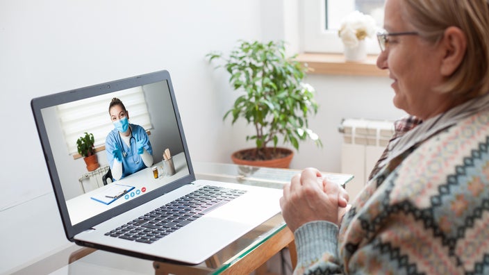 Older woman wearing a patterned sweater using her laptop for a telehealth visit with her doctor.