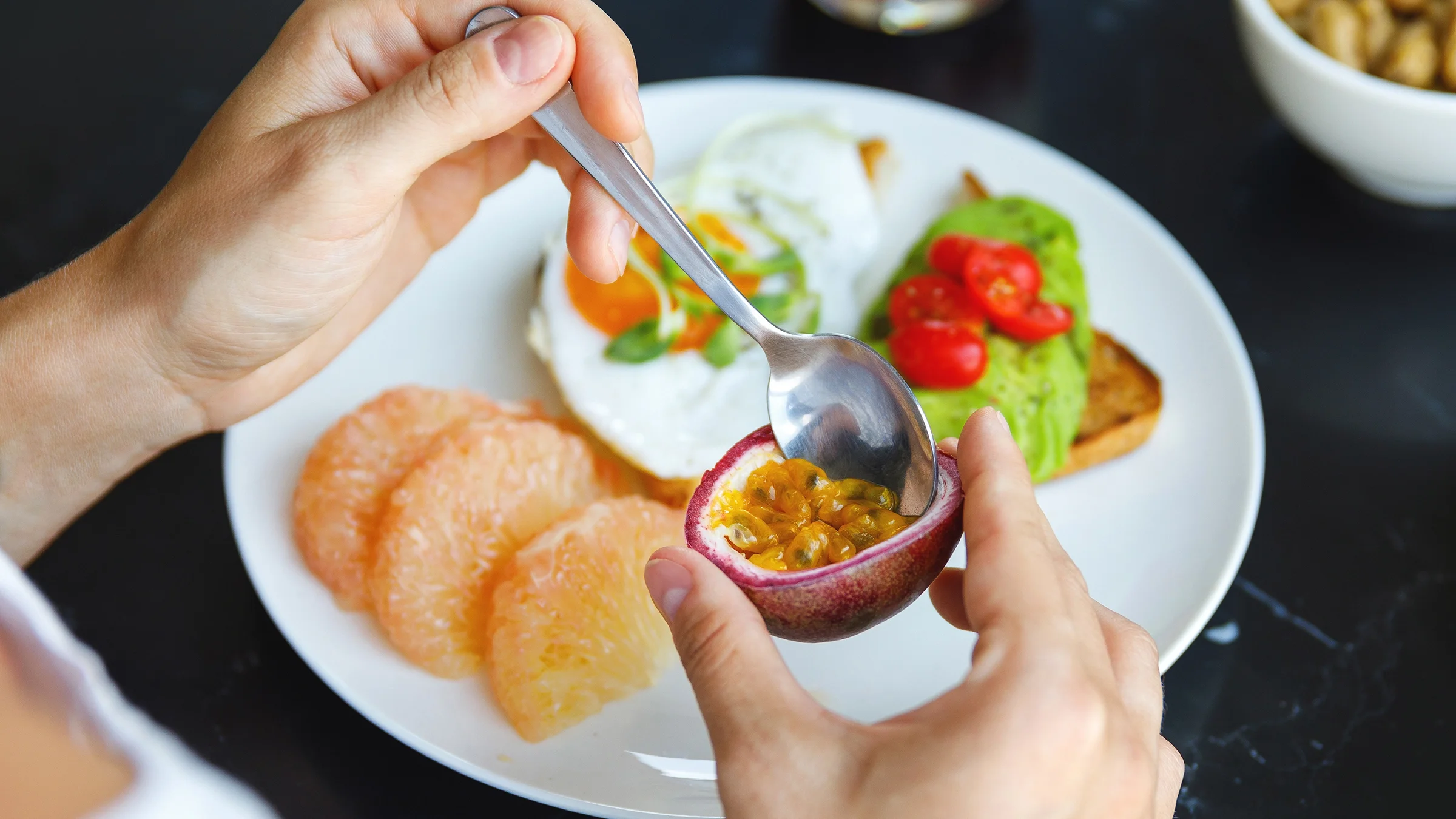 A person scoops up passion fruit seeds and pulp with a spoon.