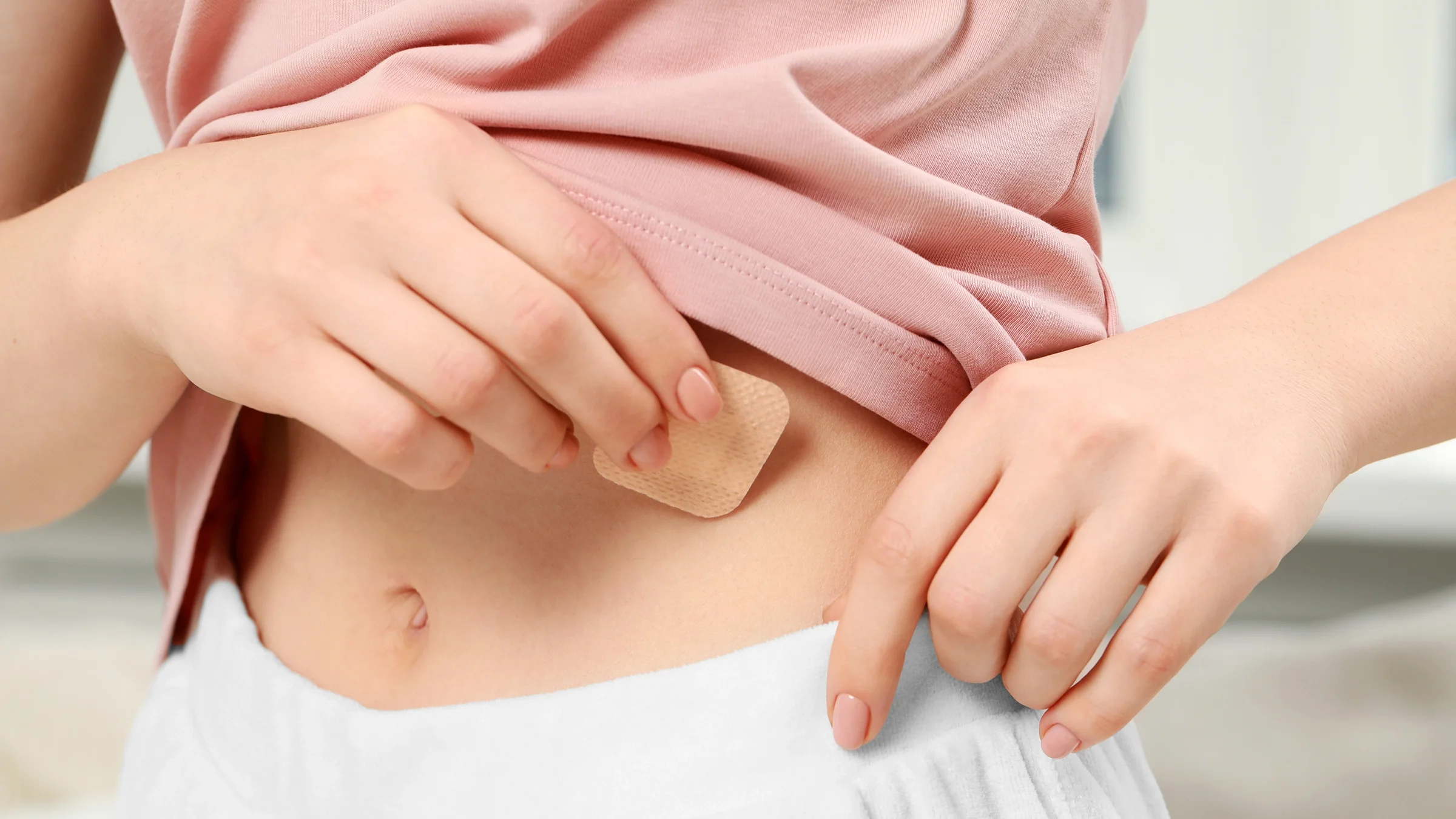 A close-up of a woman applying a contraceptive patch.