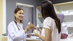 A HCP handing a pill bottle to a patient.
gahsoon/E+ via Getty Images 