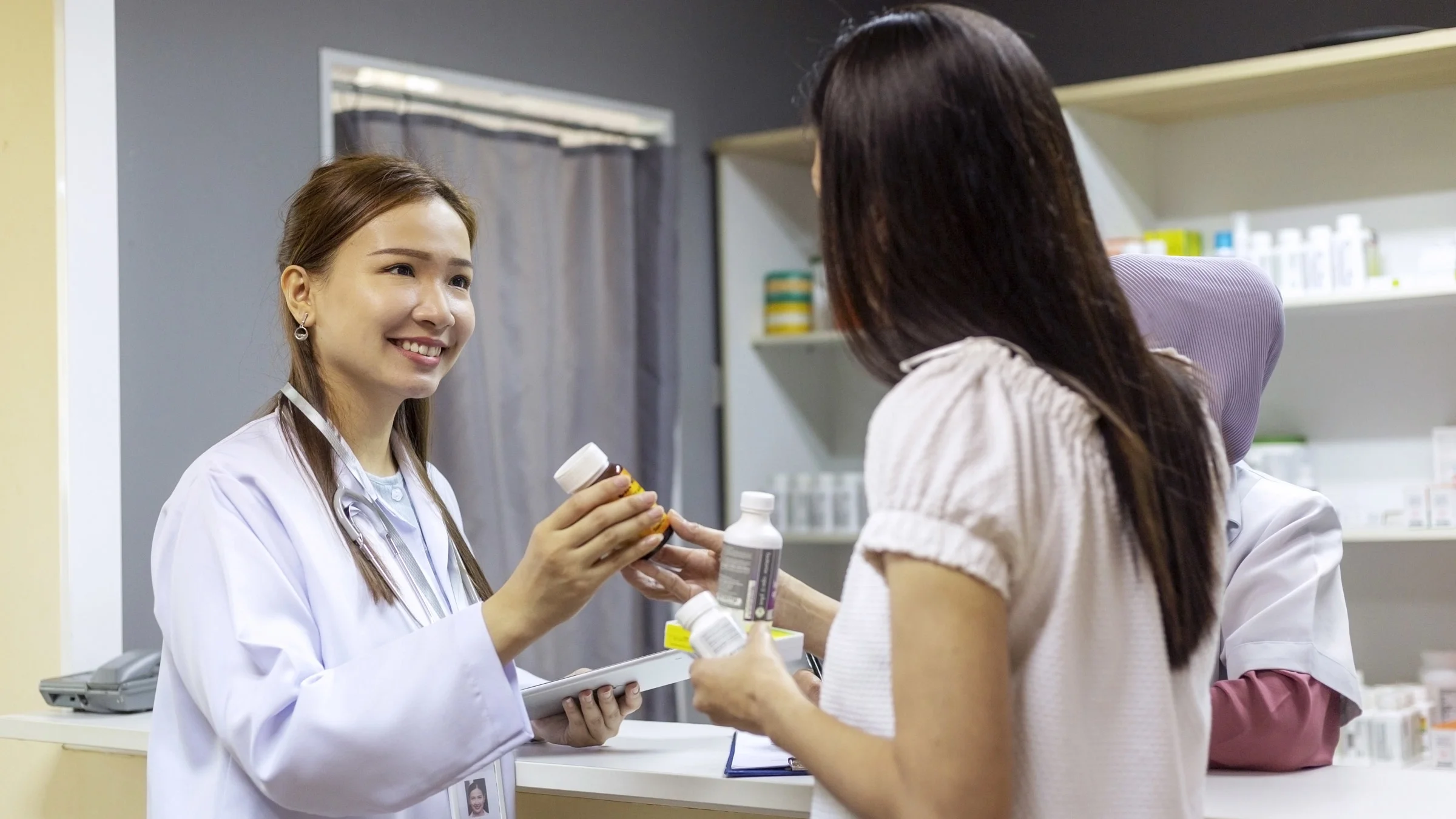 A HCP handing a pill bottle to a patient.