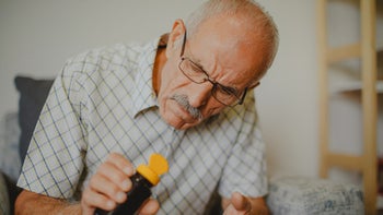 Health: Vemlidy: senior man looking-into pill bottle-1339133959