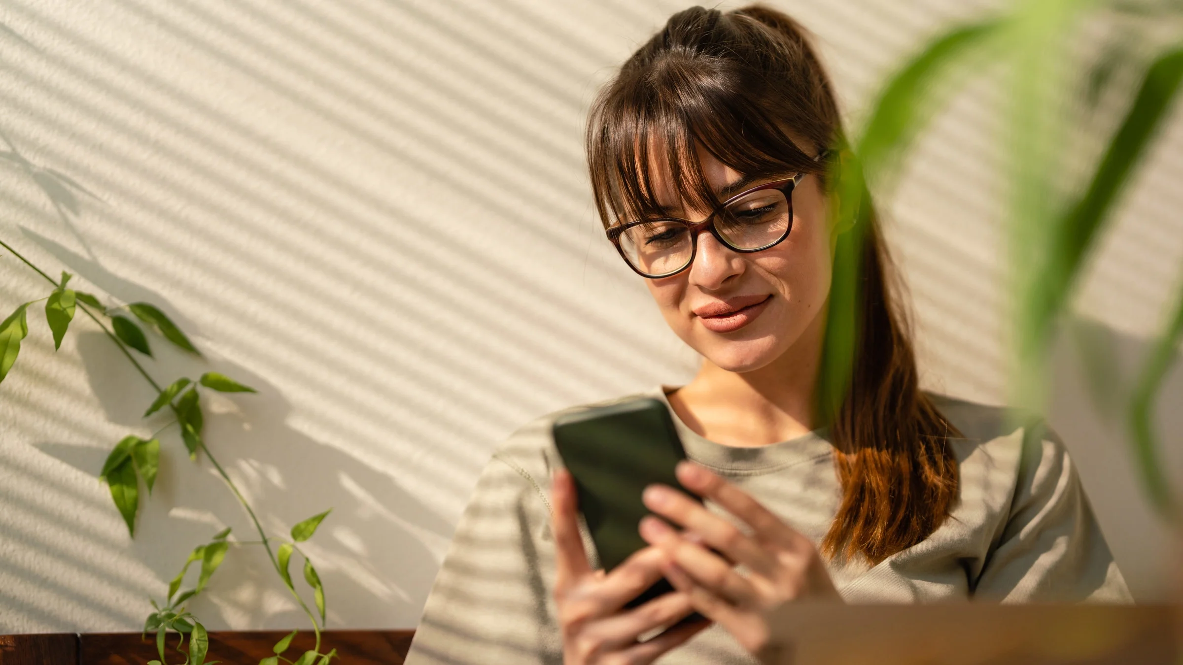 A person leaning against a wall, using their phone. 