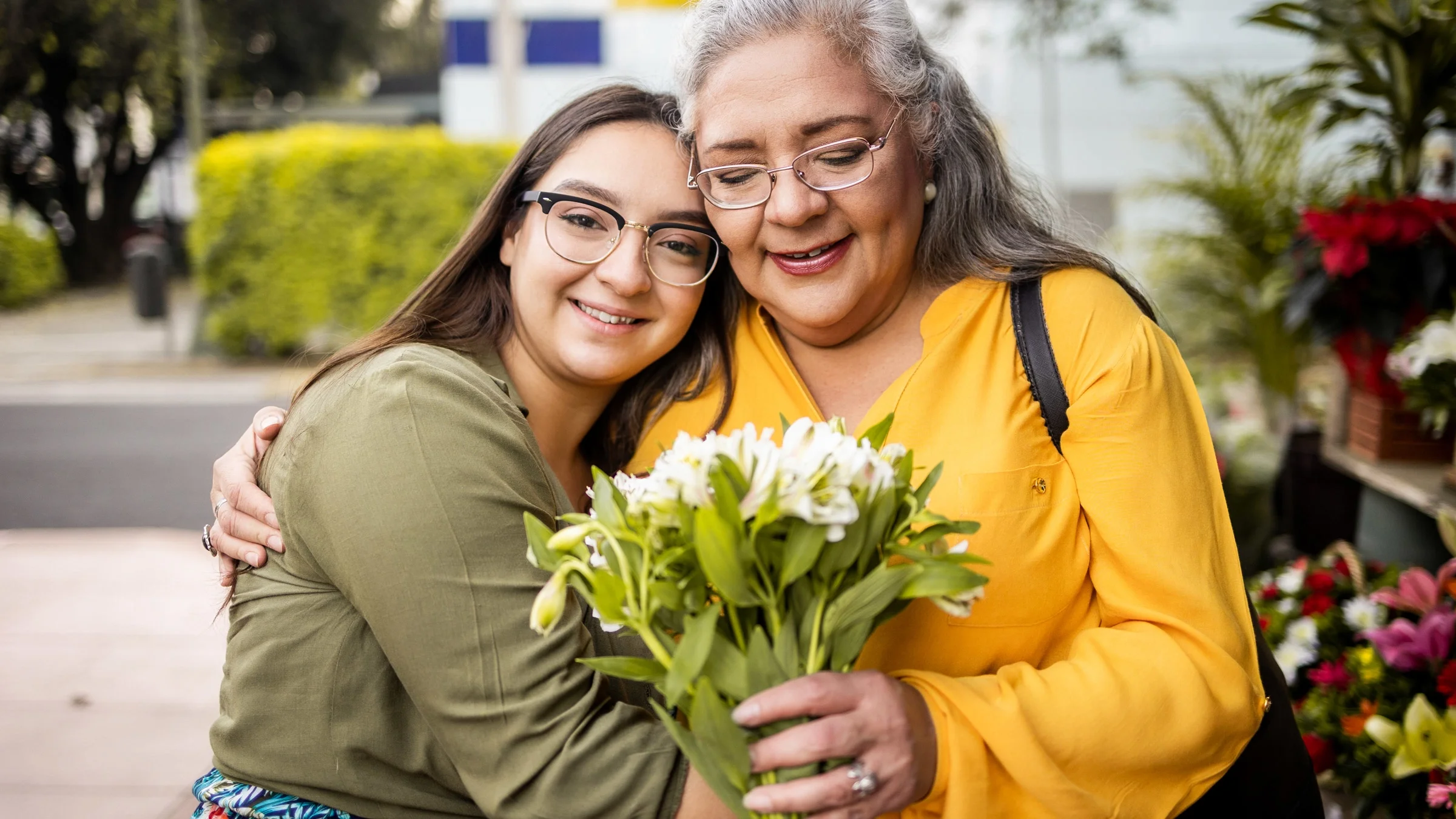 Portrait of mother and daughter hugging, holding a bouquet.