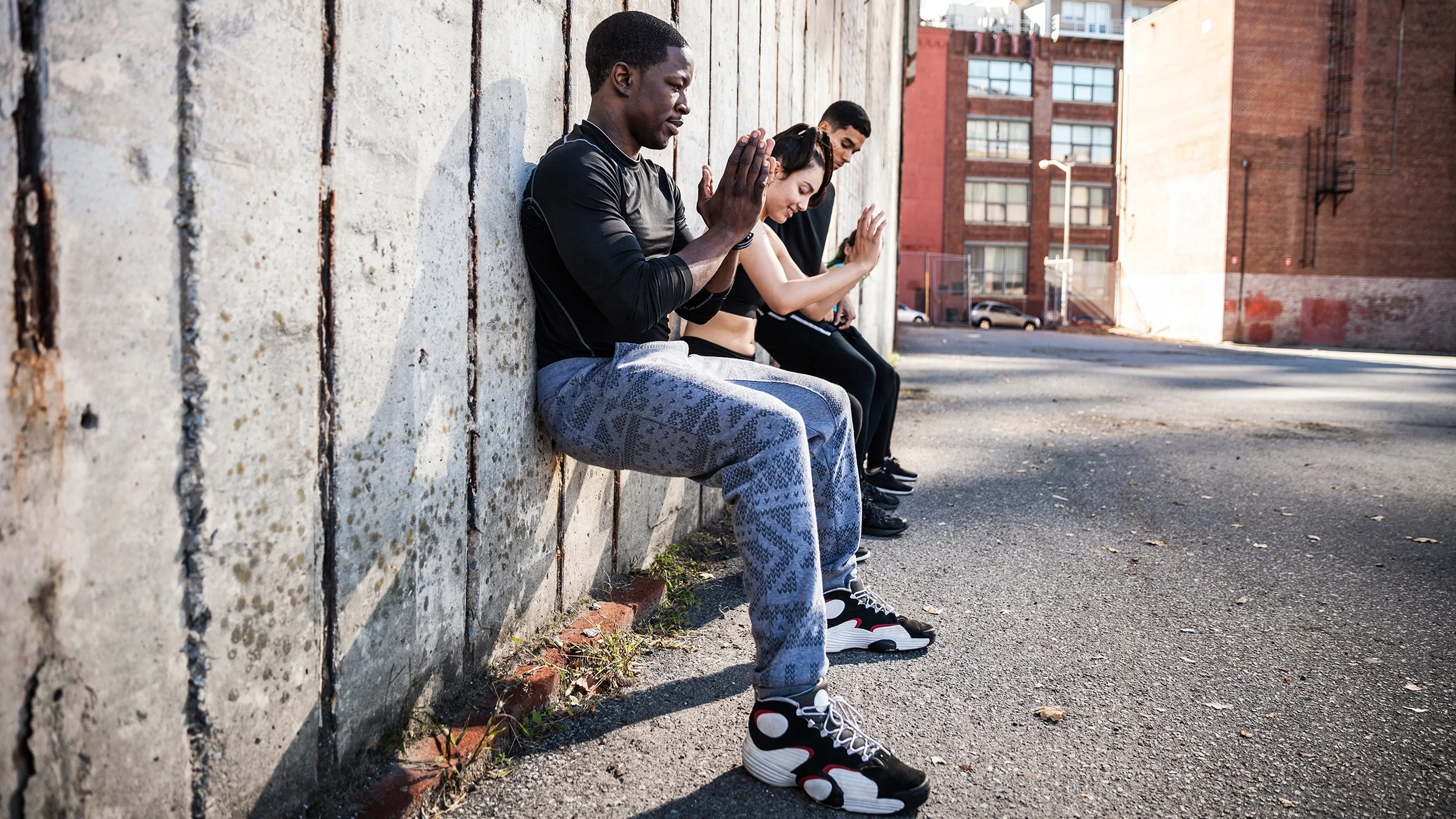 Three people doing wall sits outdoors.