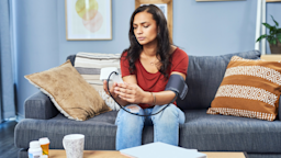 A person measuring their blood pressure in front of a table with pill bottles.
Moyo Studio/E+ via Getty Images 
