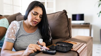Health: woman checking blood sugar at home 1384902721