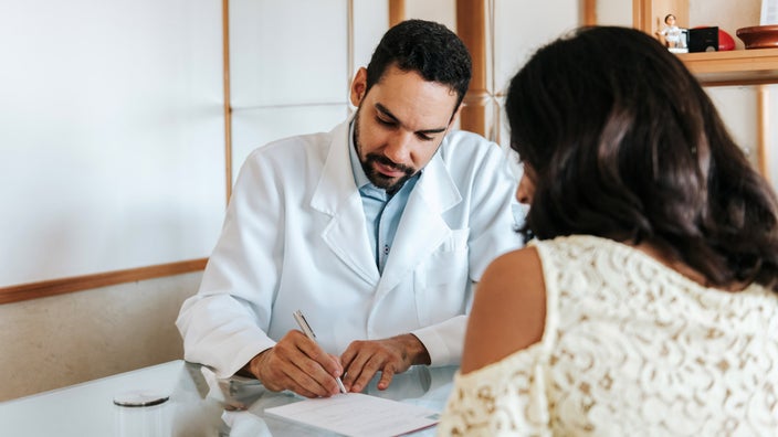 A doctor writing a prescription for a patient.