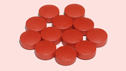 Pile of red Sudafed pills on a light pink background.
rgbdigital/iStock via Getty Images
