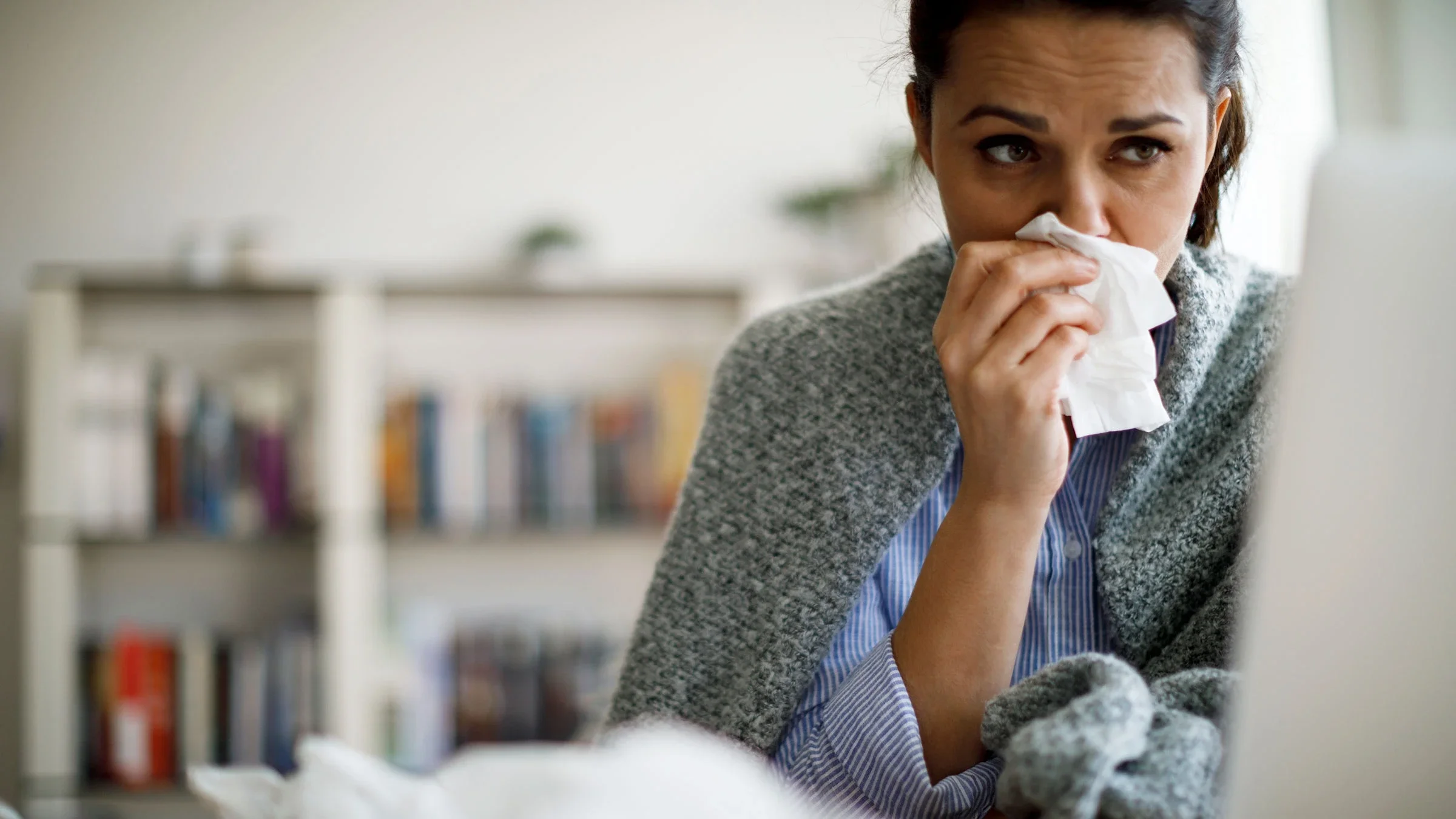 A woman is blowing her nose at home.