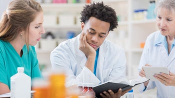 Health: Pharmacists: three pharmacists studying a book 695656404