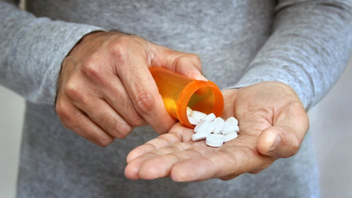 A man pours medication into the palm of his hand.