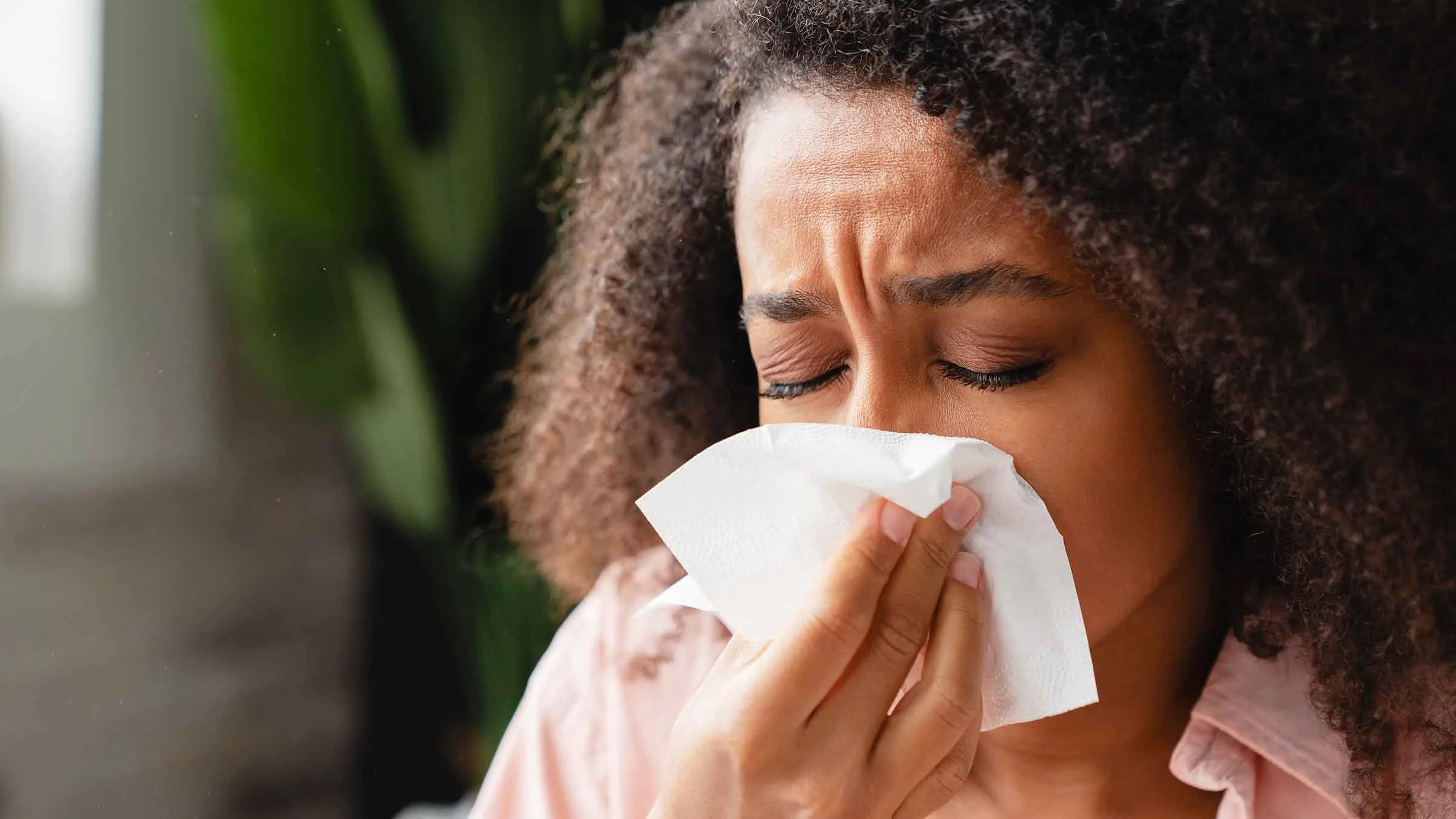A woman blows her nose due to a cold.